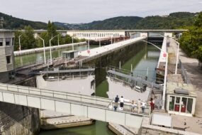 Schleusung hautnah erleben Besuchergruppe beobachtet die Einfahrt eines Schiffes in die Schleusenkammer, während der Tourguide die Funktionsweise der Schleuse erklärt.